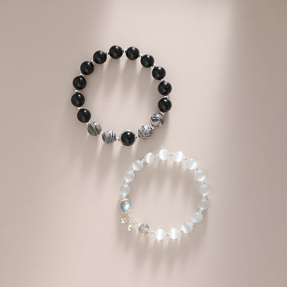 Two bracelets, one black and one white, on a neutral background.