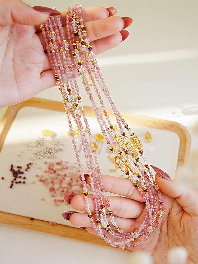 Hand holding a stack of beaded necklaces with a light background