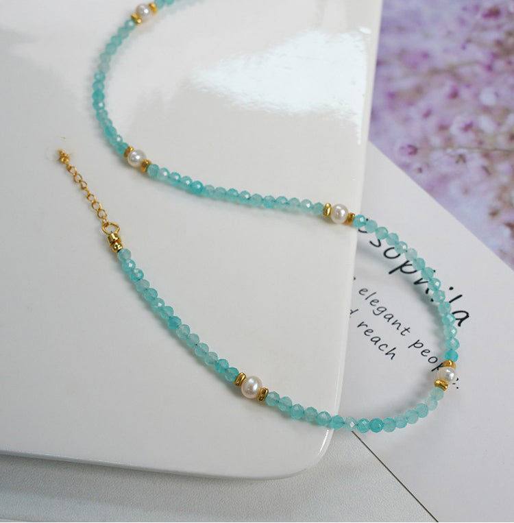 Turquoise beaded necklace with gold accents on a white surface