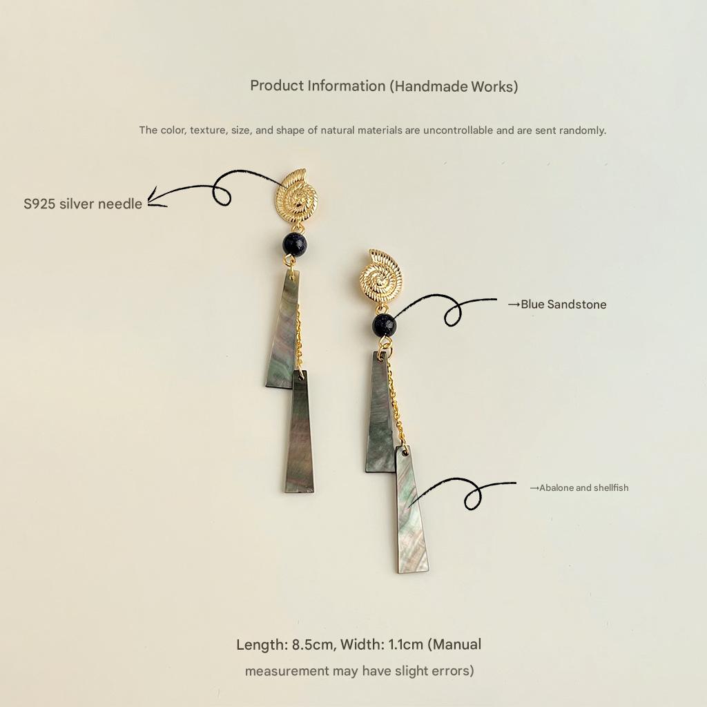 Pair of earrings with gold accents and blue sandstone elements on a light beige background