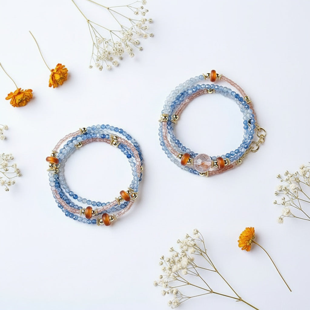Two beaded bracelets with orange and blue beads on a white background with small flowers.