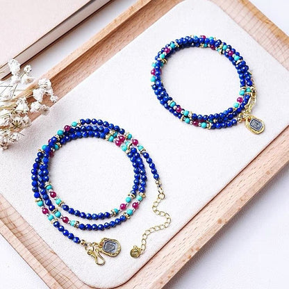 Colorful beaded bracelets with gold charms on a wooden tray