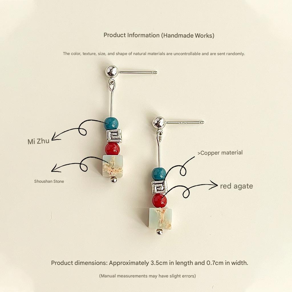 Pair of earrings with copper material, Shoushan stone, and red agate on a beige background.
