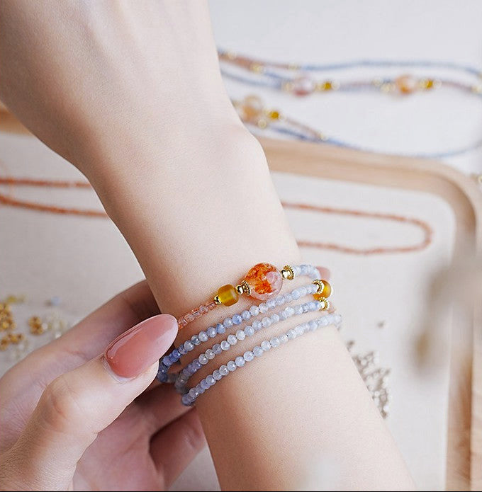 Close-up of a wrist with multiple beaded bracelets on a soft background