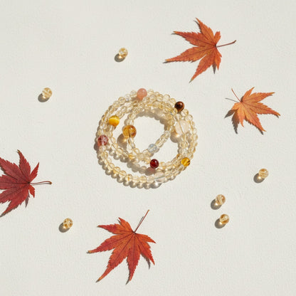 Stack of beaded bracelets with red and orange leaves on a light background