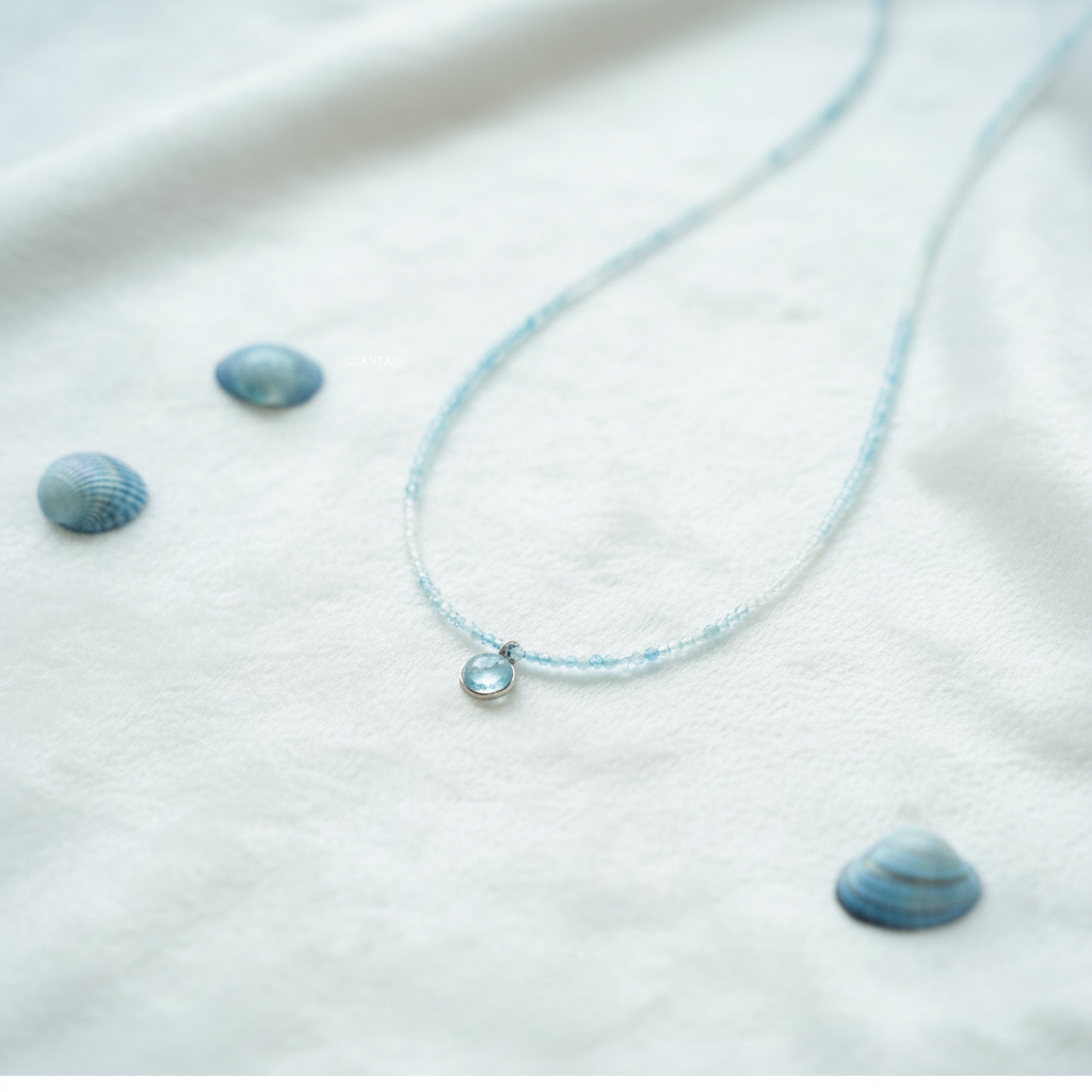 Necklace with small blue stones on a white fabric background
