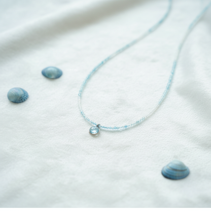 Necklace with small blue stones on a white fabric background