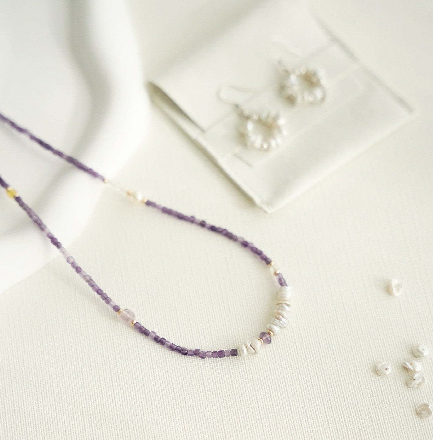 Purple beaded necklace and earrings on a light background