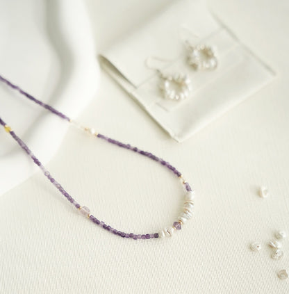 Purple beaded necklace and earrings on a light background