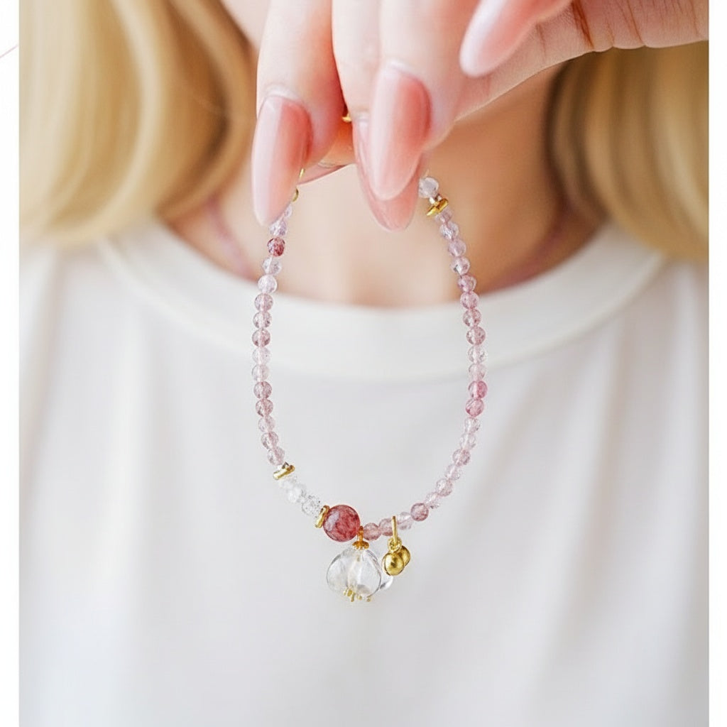Delicate bracelet with pink beads and gold accents held by a hand against a white background