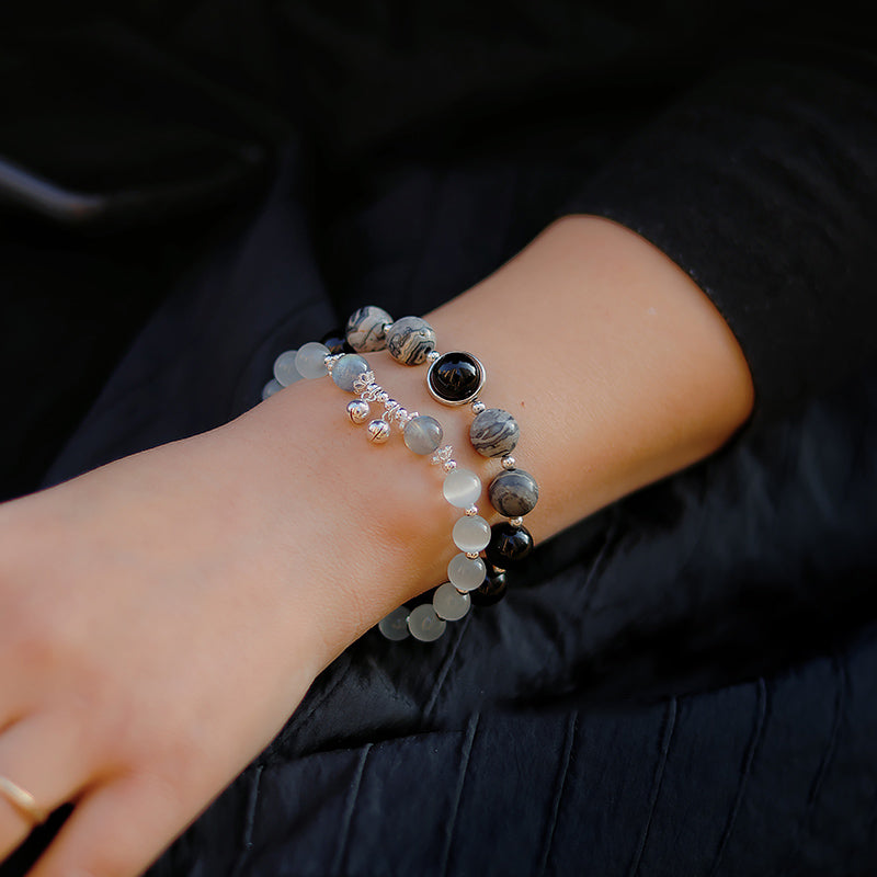 Close-up of a wrist with beaded bracelets against a dark background.