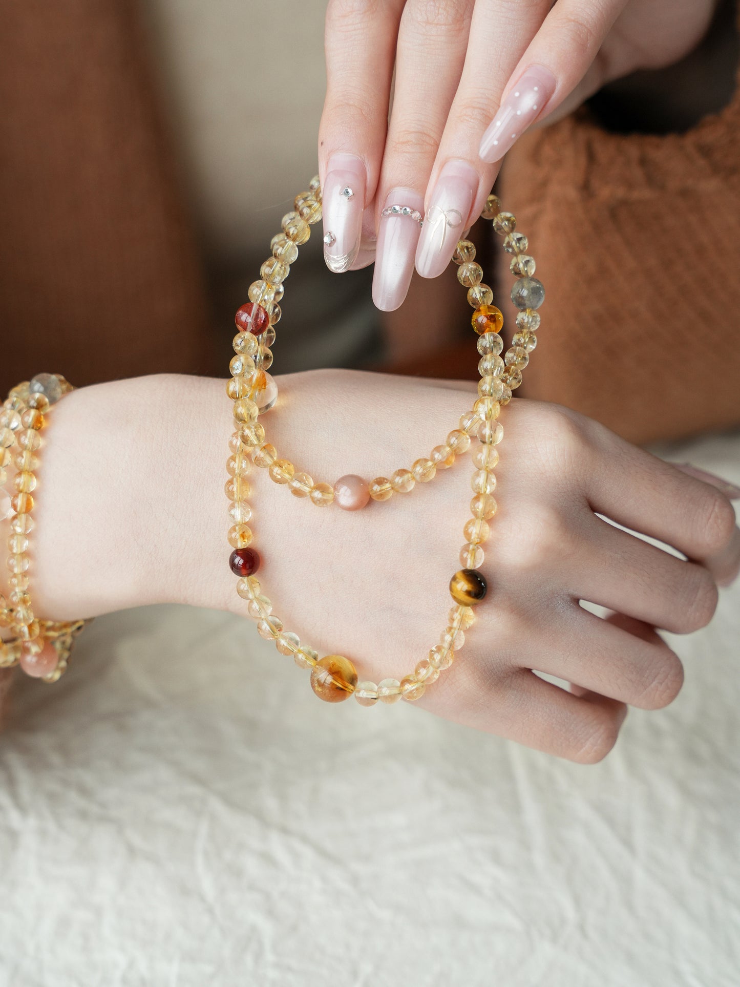 Close-up of a hand wearing multiple beaded bracelets on a neutral background