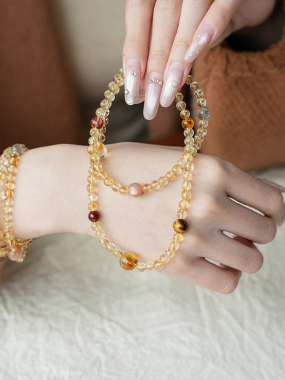 Close-up of a hand wearing multiple beaded bracelets on a neutral background