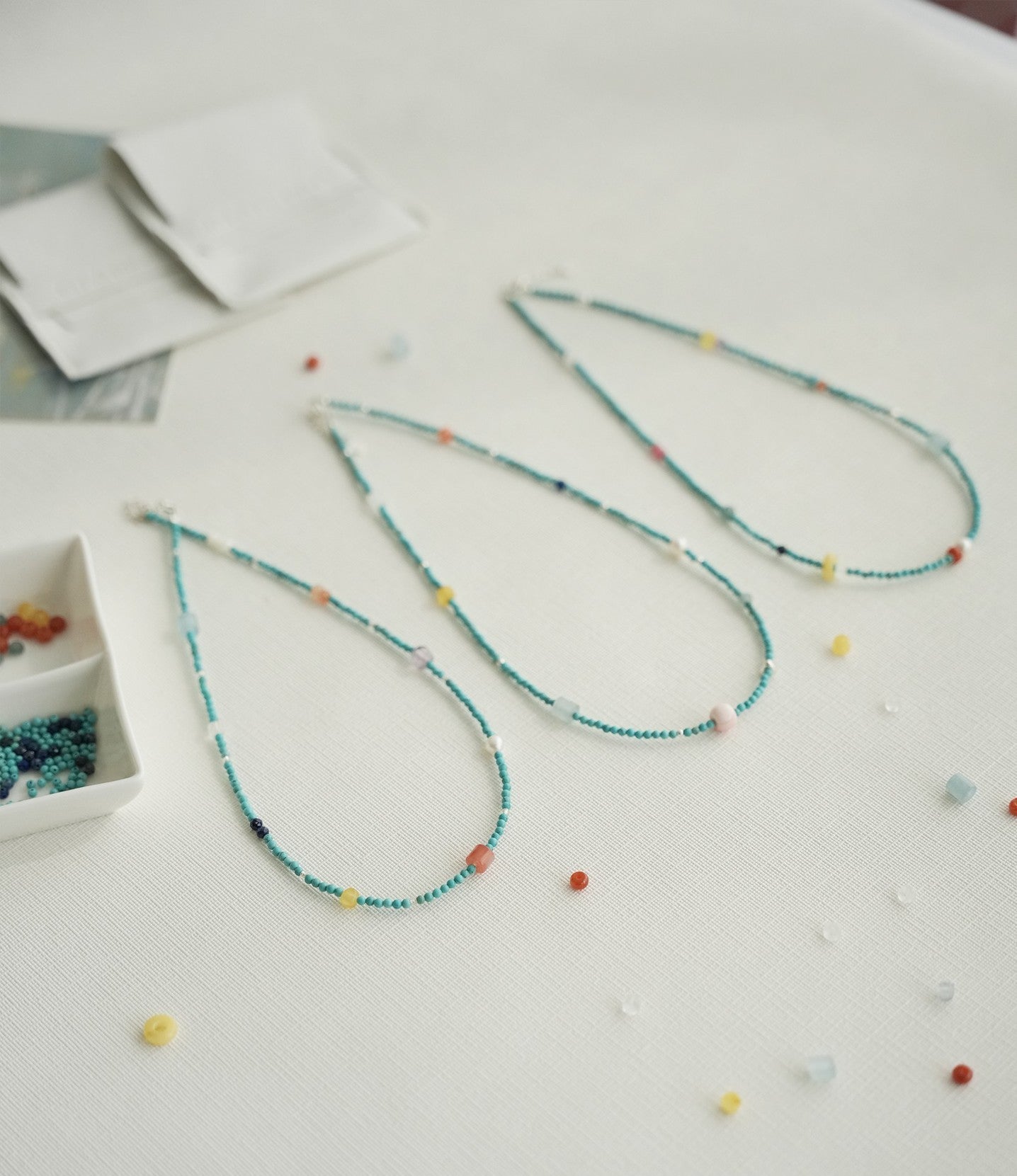 Colorful beaded necklace on a light surface with scattered beads.