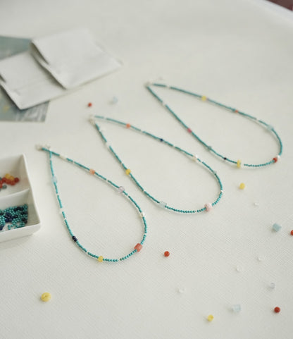 Colorful beaded necklace on a light surface with scattered beads.