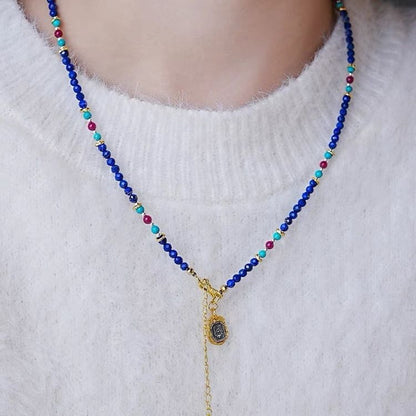 Necklace with blue beads and a gold chain on a white sweater