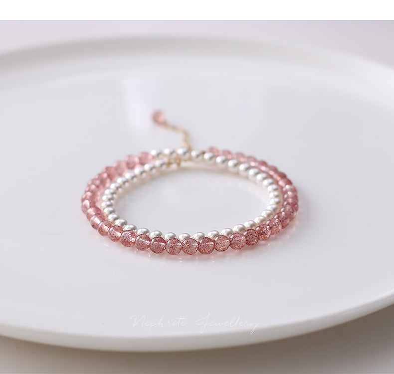 Two beaded bracelets, one pink and one silver, on a white plate.