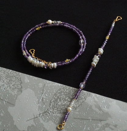 Purple beaded necklace with gold accents on a black and gray gradient background