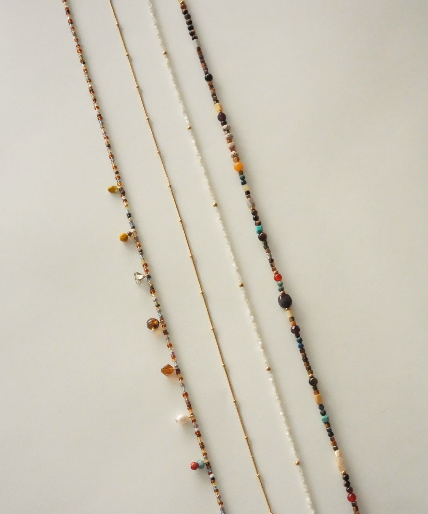 Three beaded necklaces on a light wooden surface