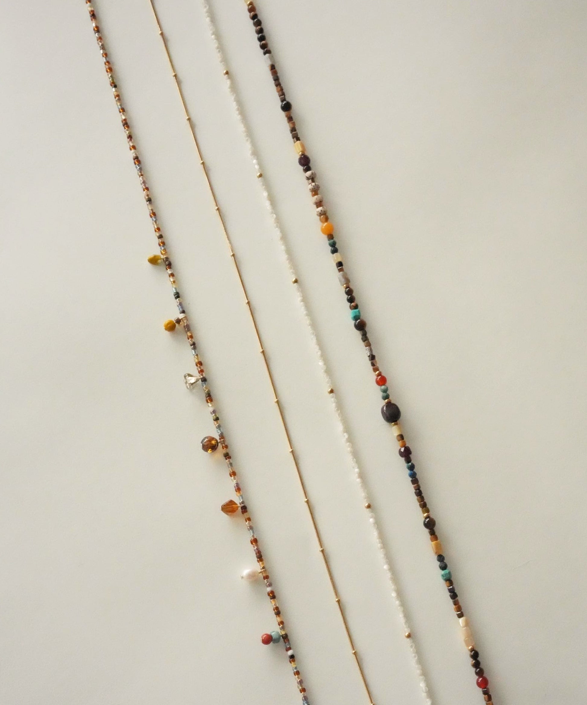 Three beaded necklaces on a light wooden surface