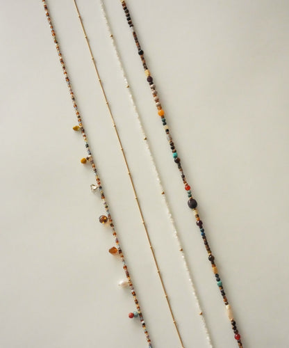 Three beaded necklaces on a light wooden surface