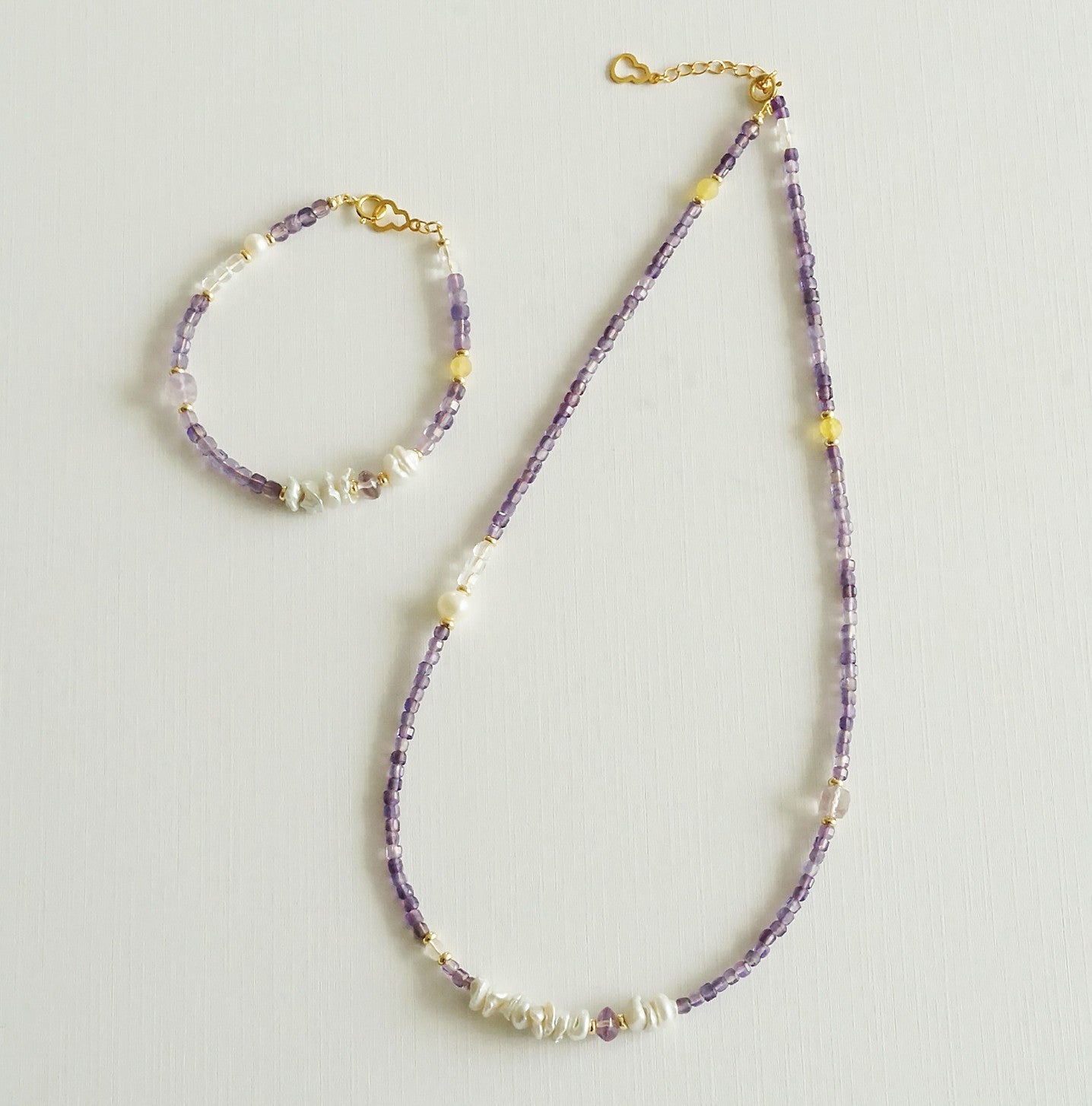 Beaded necklace and bracelet set on a light gray background
