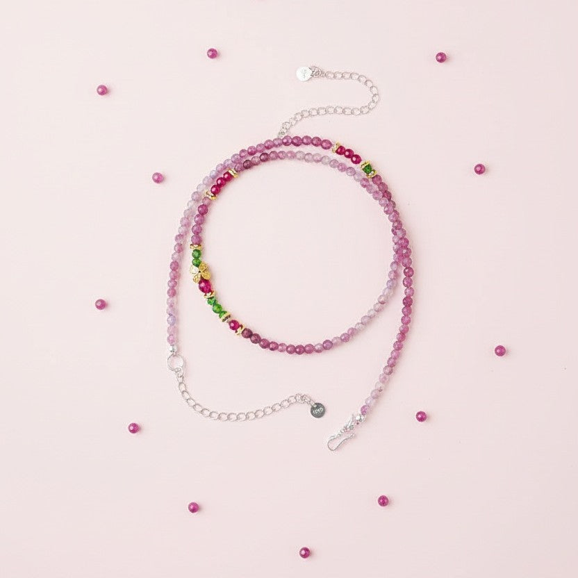 Beaded necklace with pink and green beads on a light pink background