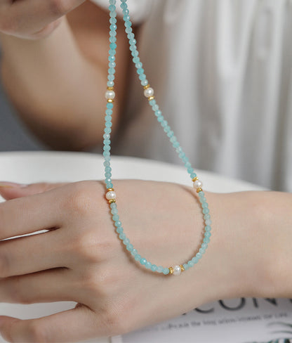 Close-up of a hand wearing a beaded necklace with small pearls.