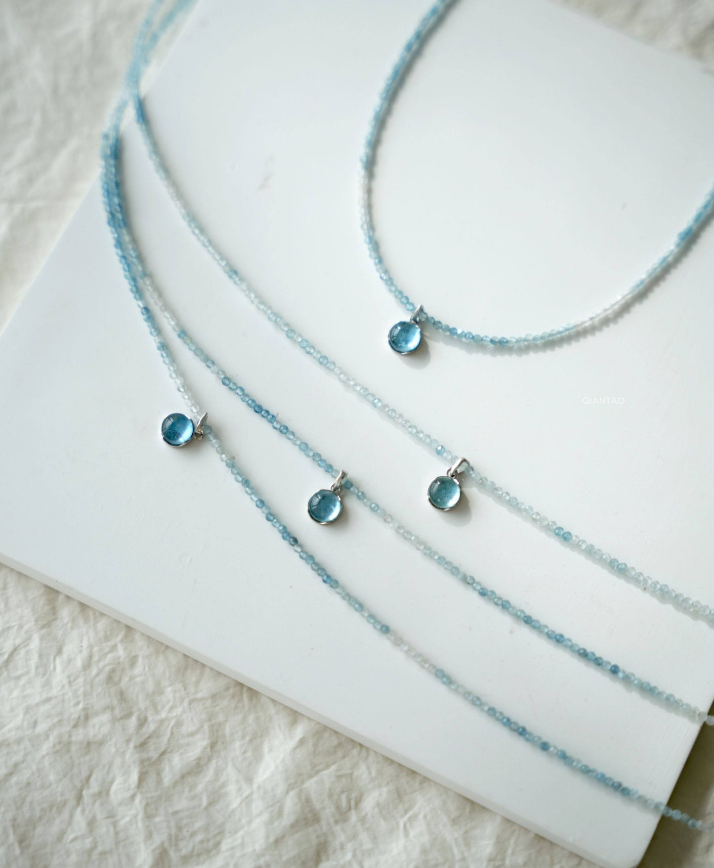 Three blue beaded necklaces on a white surface