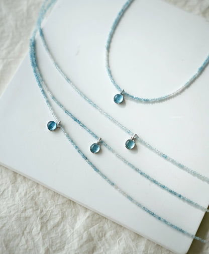 Three blue beaded necklaces on a white surface