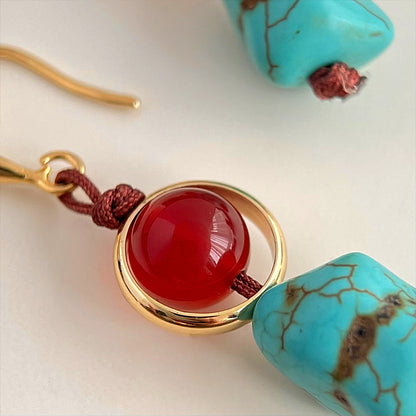 Earrings with red gemstone and turquoise beads on a light background