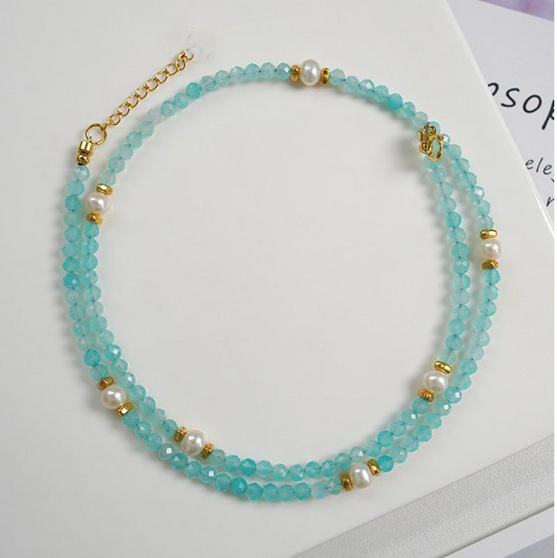 Two turquoise beaded necklaces with gold accents on a white surface.