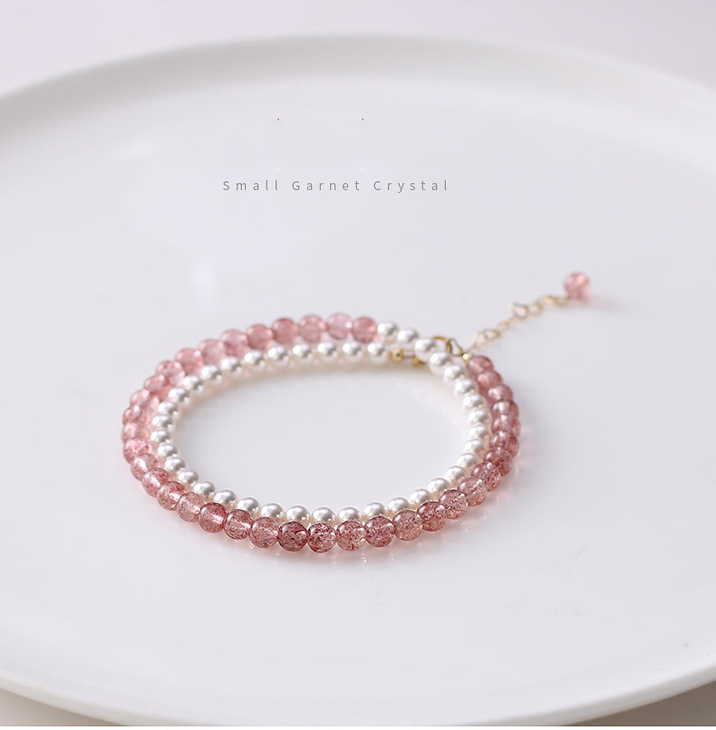 Two beaded bracelets, one pink and one silver, on a white surface.
