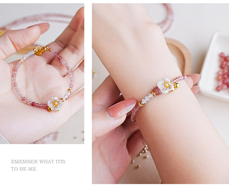 Close-up of a hand wearing a delicate bracelet with pink beads and gold accents.