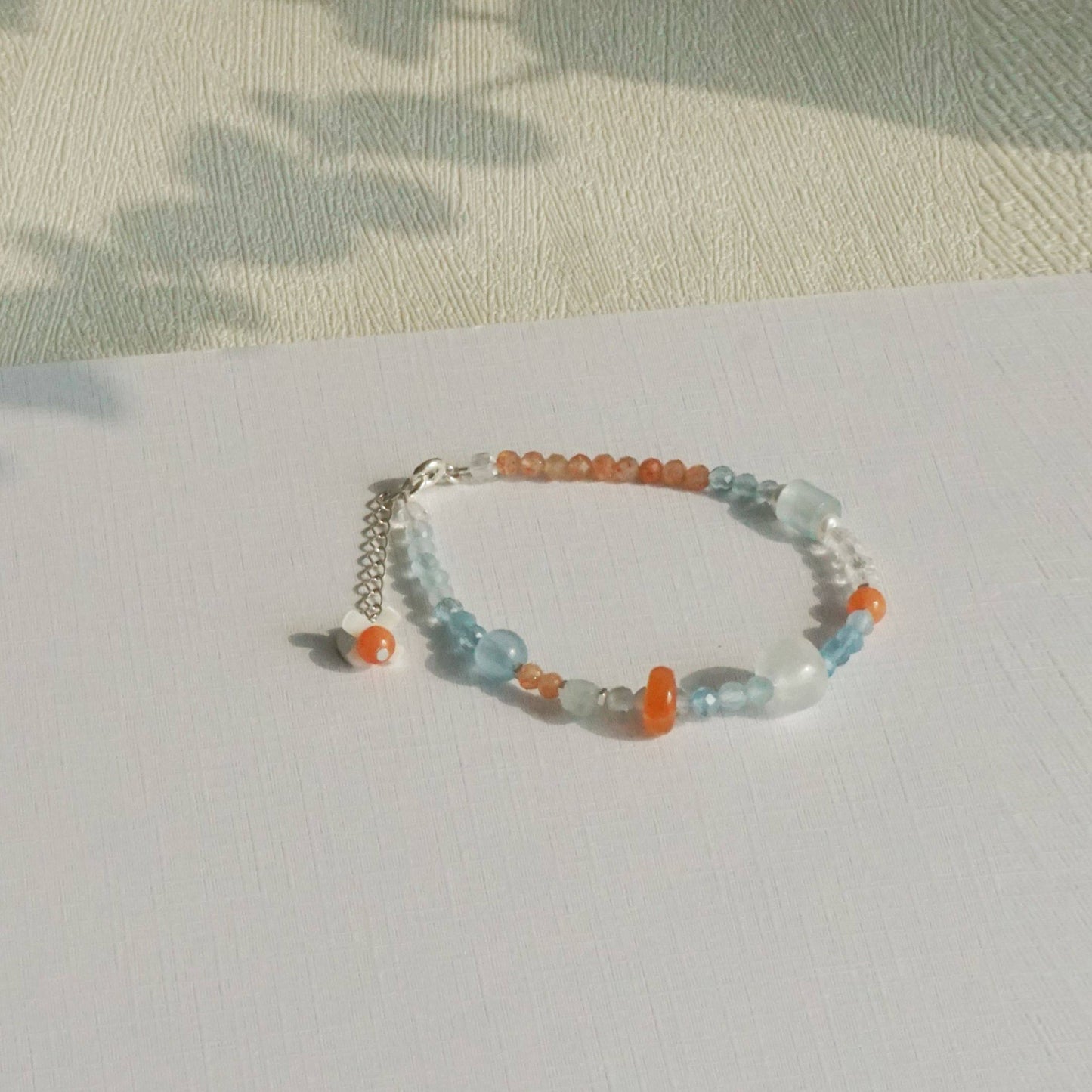 Beaded bracelet with orange and blue beads on a light surface