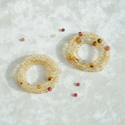 Two beaded bracelets on a textured white surface with scattered beads.