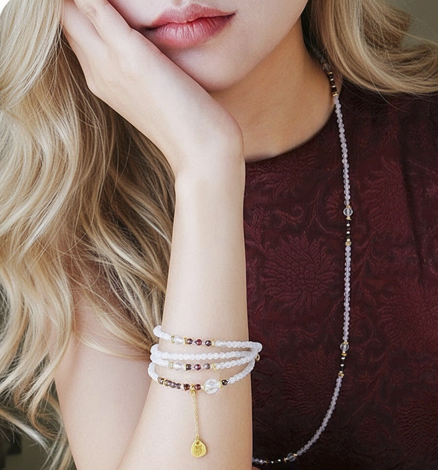 Woman wearing multiple pearl bracelets on her wrist with a blurred background