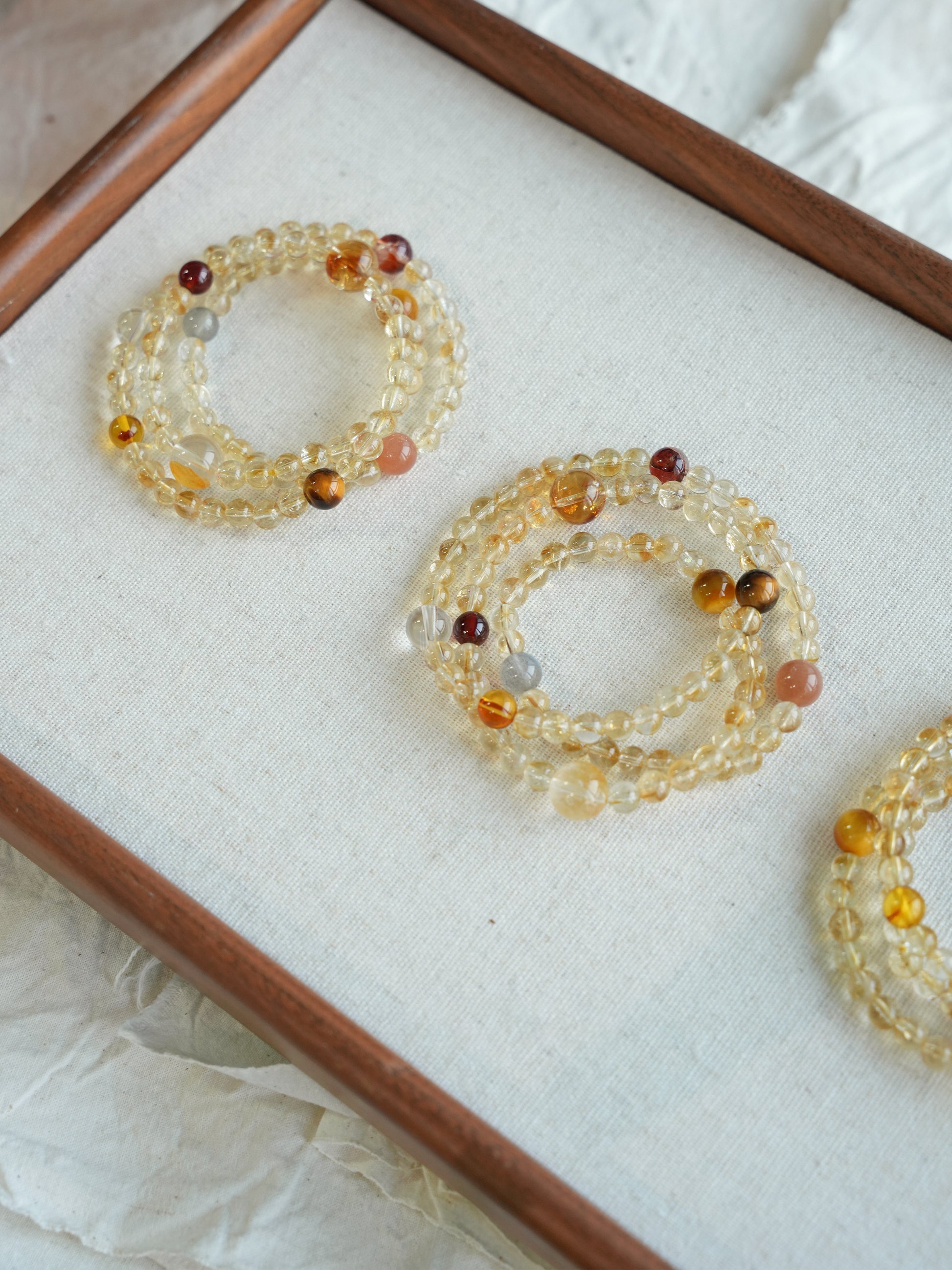 Set of beaded bracelets on a white cushion with a wooden frame