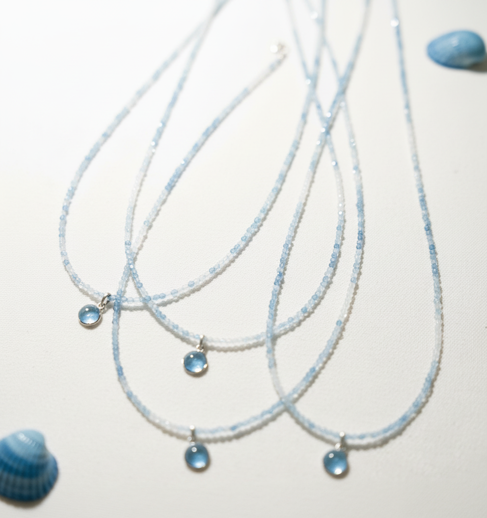 Three blue beaded necklaces on a light background with blue shells.