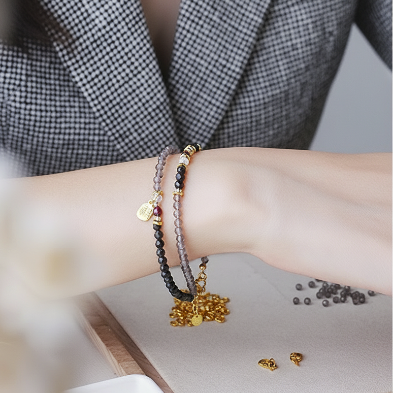 Close-up of a person's wrist with multiple bracelets and earrings on a blurred background