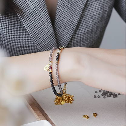 Close-up of a person's wrist with multiple bracelets and earrings on a blurred background