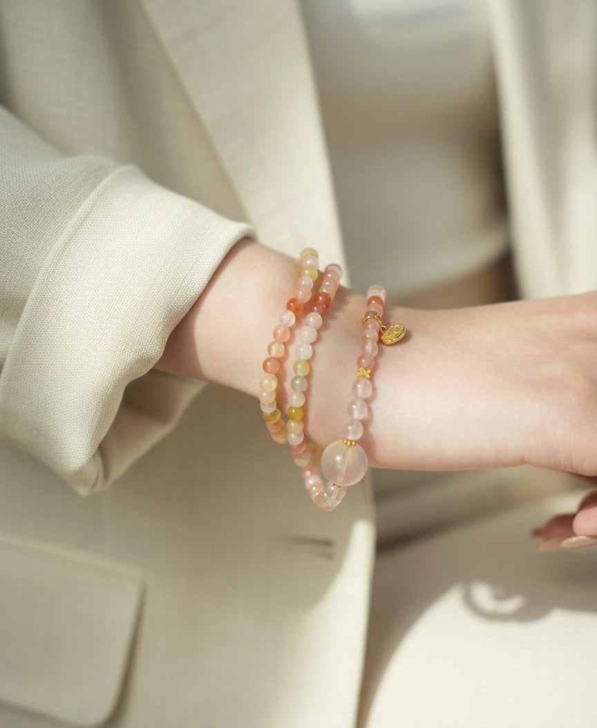 Close-up of a person wearing two beaded bracelets on a neutral background