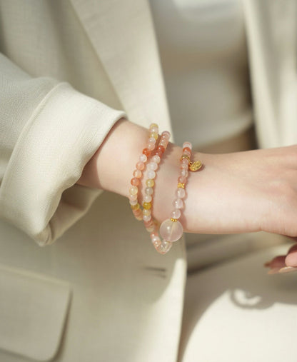 Close-up of a person wearing two beaded bracelets on a neutral background