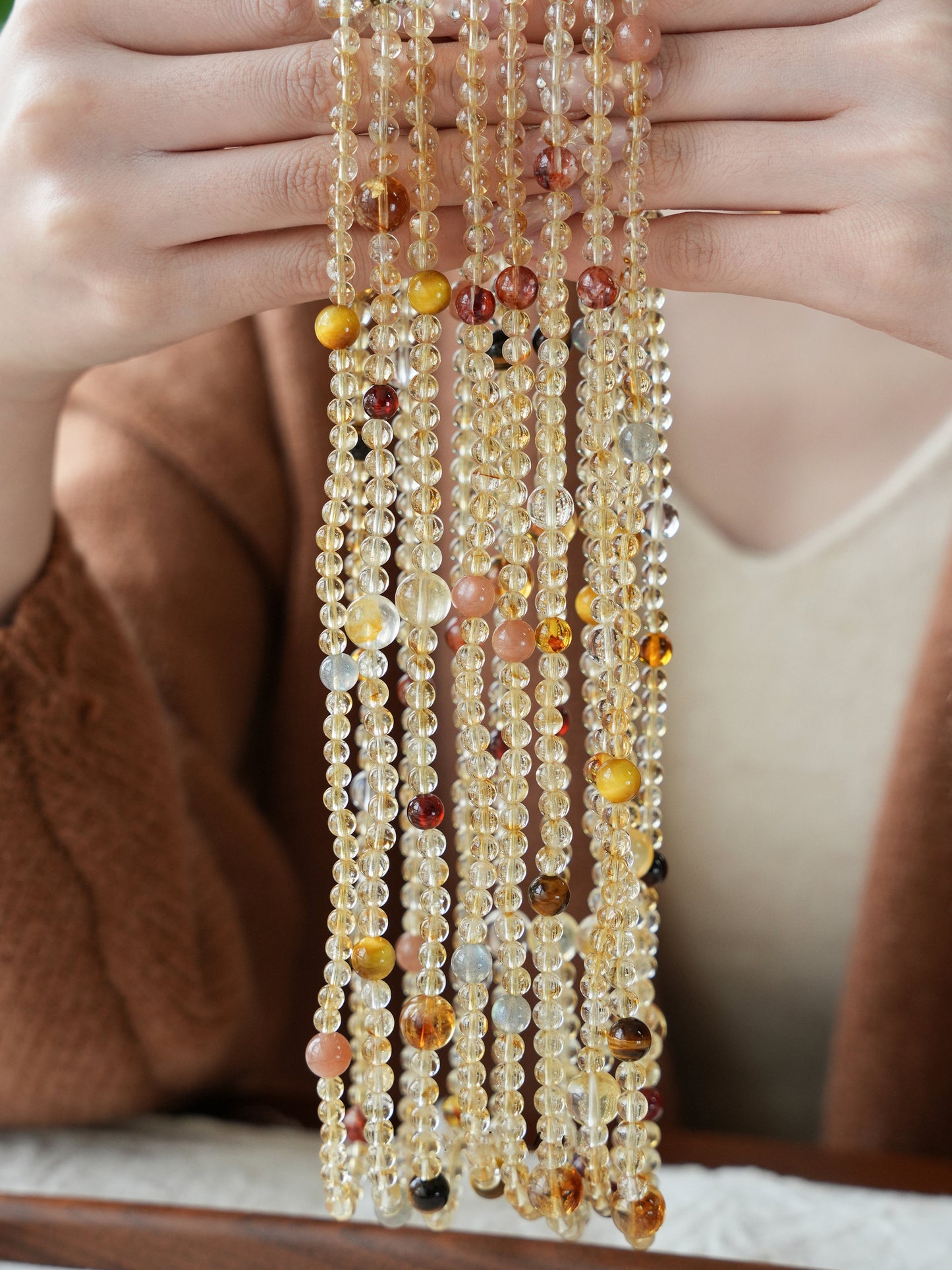 Multistrand beaded necklace held by a person with a blurred background