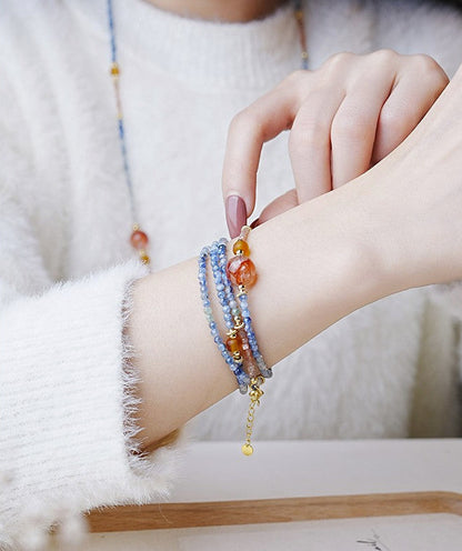 Close-up of a hand wearing multiple colorful beaded bracelets on a soft white background.