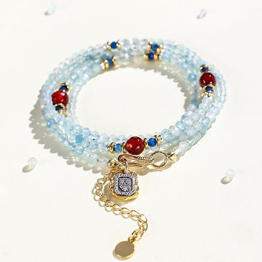 Multistrand beaded bracelet with gold charm on a white background