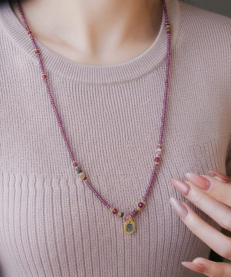 Person wearing a beaded necklace with a pink sweater