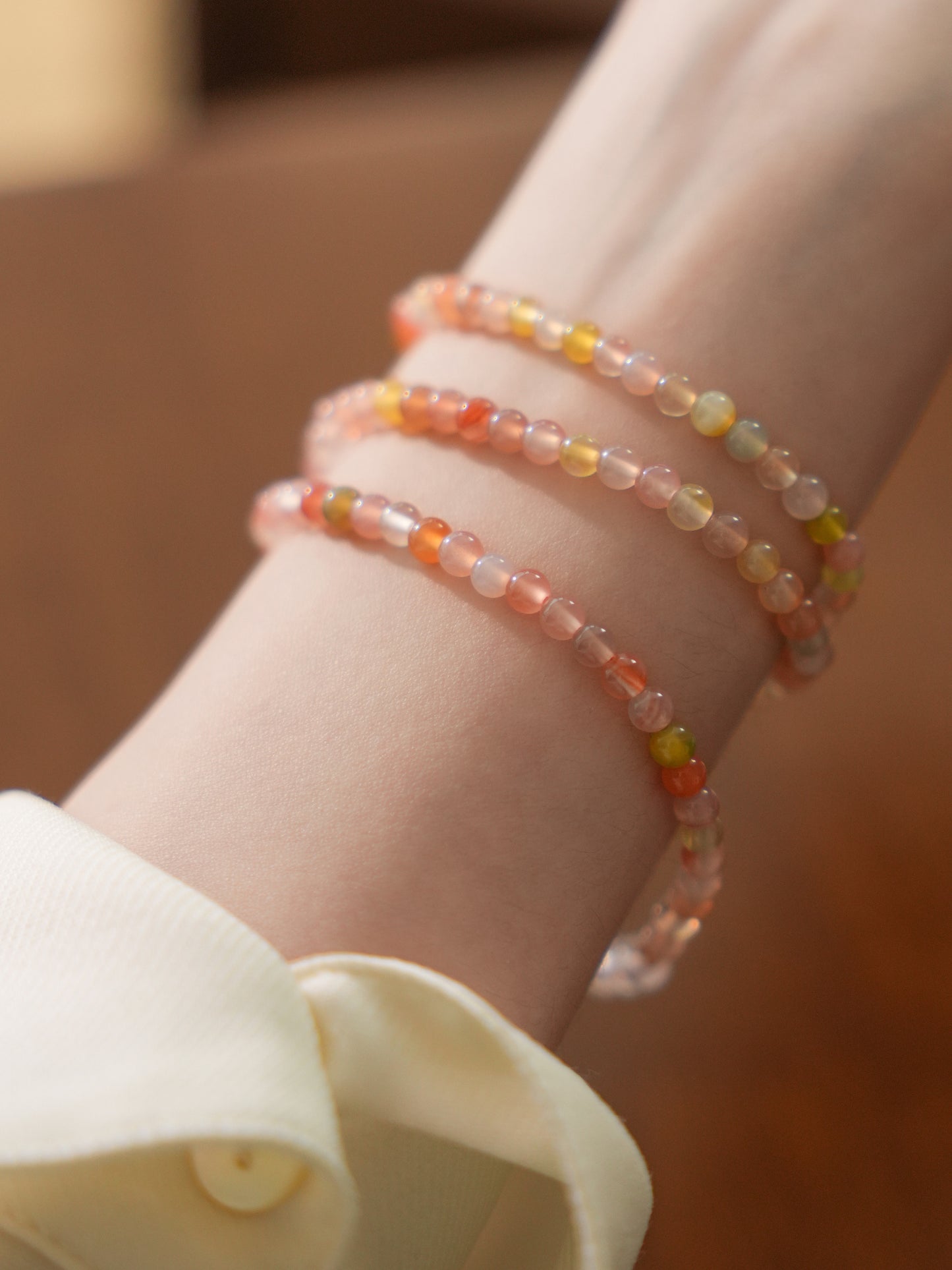 Close-up of a wrist wearing two beaded bracelets on a blurred background