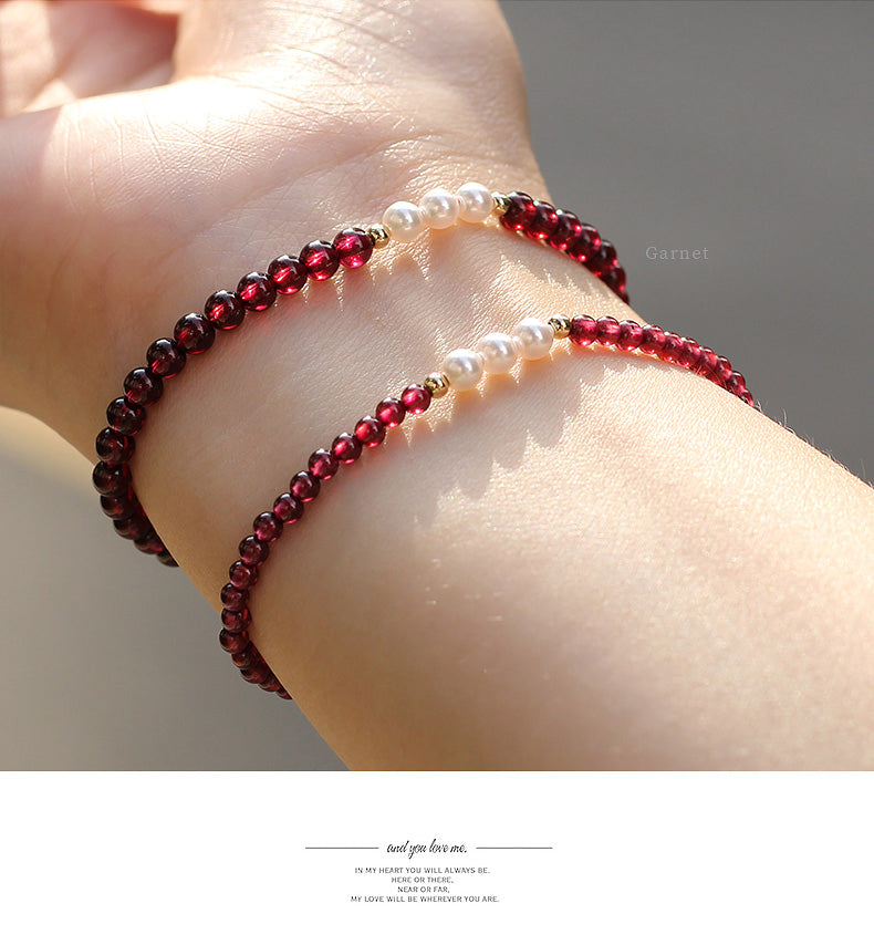 Close-up of a wrist with two beaded bracelets on a neutral background.