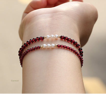 Close-up of a wrist wearing two beaded bracelets against a neutral background.
